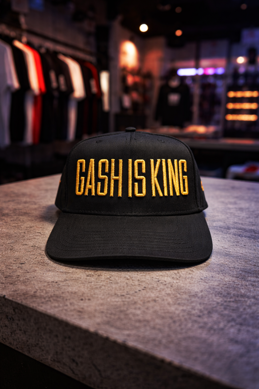 Black cap with 'GASH IS KING' in yellow on a concrete surface with a store background.