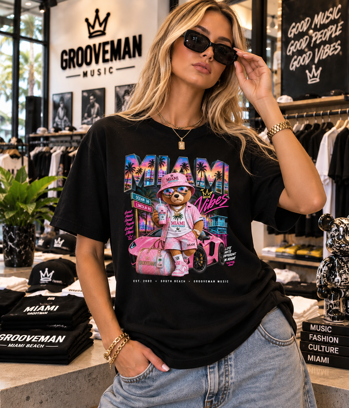 A woman wearing a black Grooveman Music graphic t-shirt with a colorful cartoon bear design, standing inside a music-themed boutique.