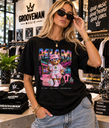 A woman wearing a black Grooveman Music graphic t-shirt with a colorful cartoon bear design, standing inside a music-themed boutique.