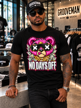 Model leaning against a concrete table in the black No Days Off pink teddy bear graphic T-shirt inside Grooveman.
