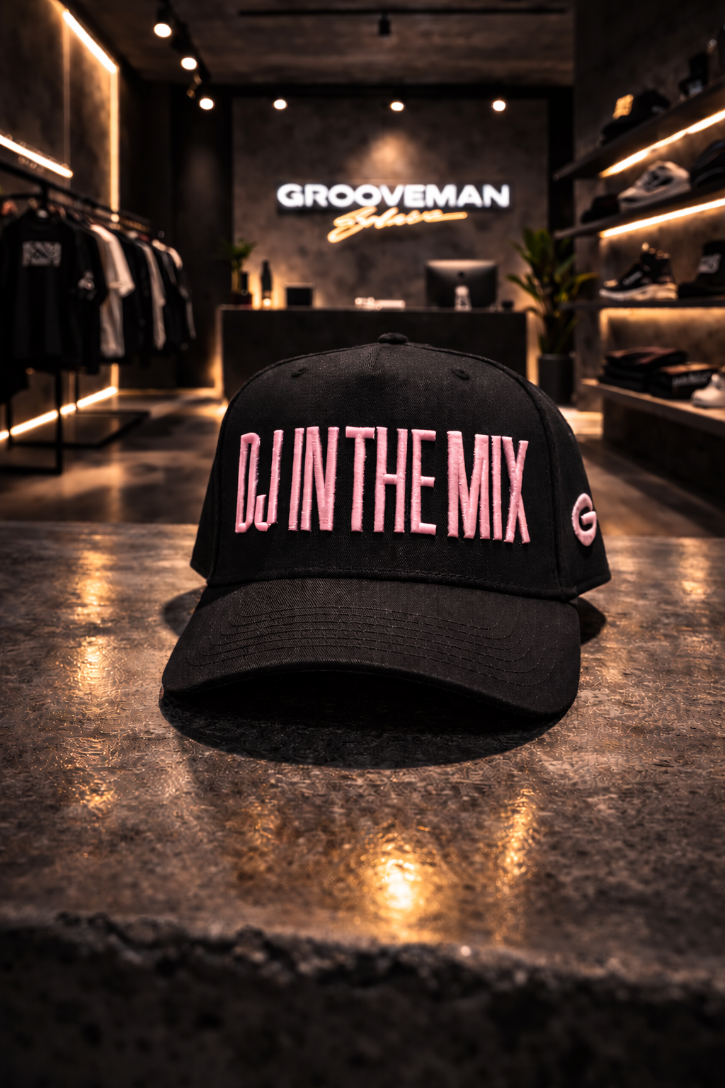 Black cap with 'DJ IN THE MIX' text on a reflective surface in a store setting.