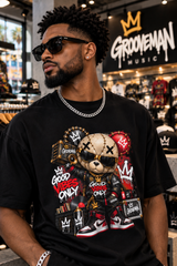 A man wearing a black Groovemusic t-shirt with a large cartoon bear graphic, styled with sunglasses and a silver chain necklace in a retail store setting.