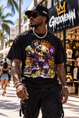 A man walking down a sunny street wearing a black crewneck t-shirt with a large, colorful graphic print featuring a cartoon bear wearing a gold crown and sunglasses, surrounded by money, sneakers, and the words 'GRIND' and 'INSPIRE'.