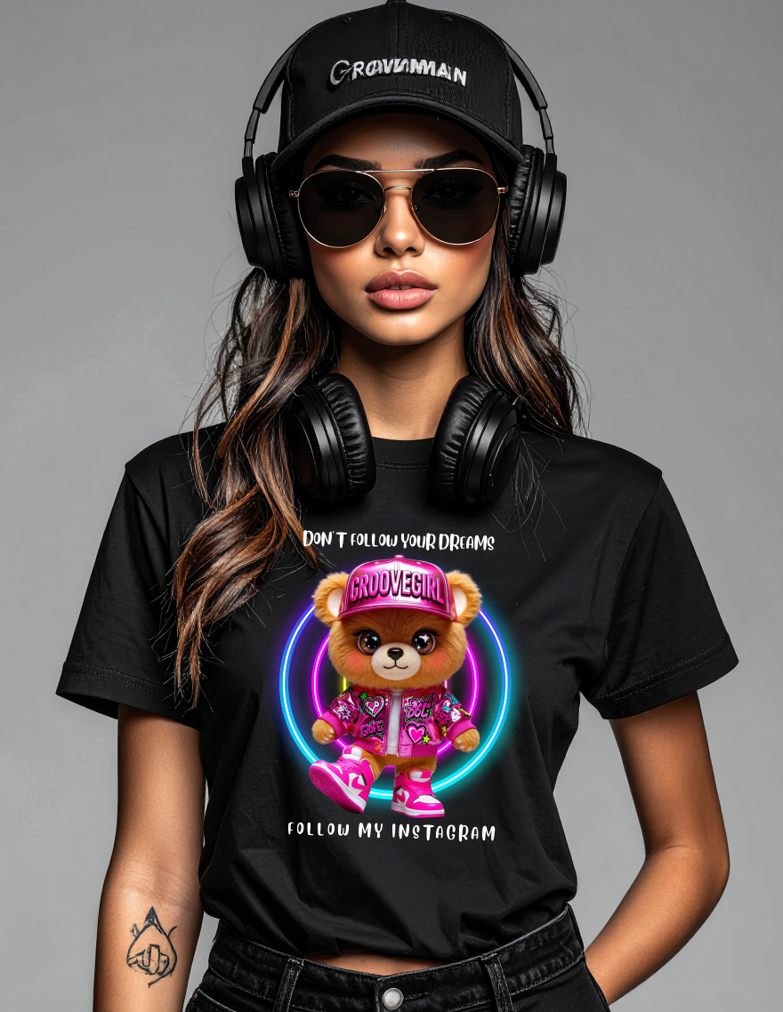 Person wearing a black t-shirt with a teddy bear graphic and text, black cap, and headphones.