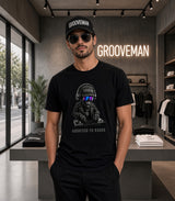 A man wearing a black t-shirt with a graphic of a DJ wearing headphones and the text 'ADDICTED TO HORNSE' stands in a modern clothing store. The t-shirt features a black and white graphic with a small pink accent on the sunglasses.