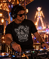Male DJ performing at a nighttime desert rave wearing Grooveman God Is A DJ graphic T-shirt