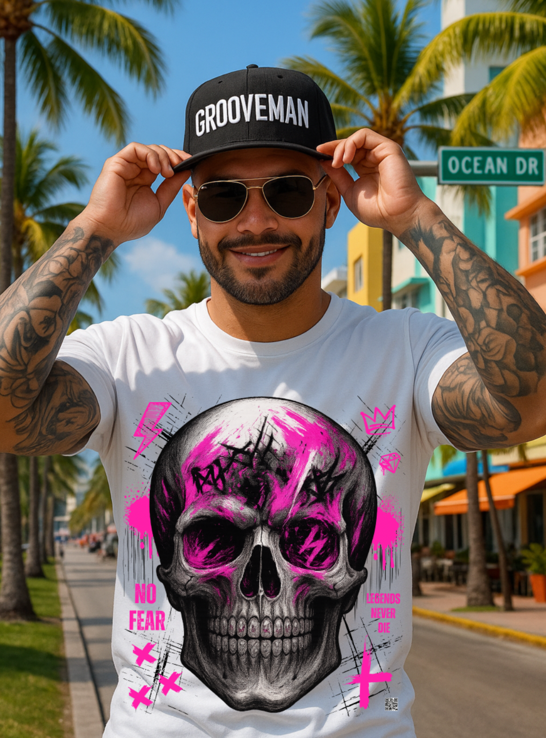 Man wearing a white t-shirt with a skull design and 'Grooveman' cap on a street with palm trees.