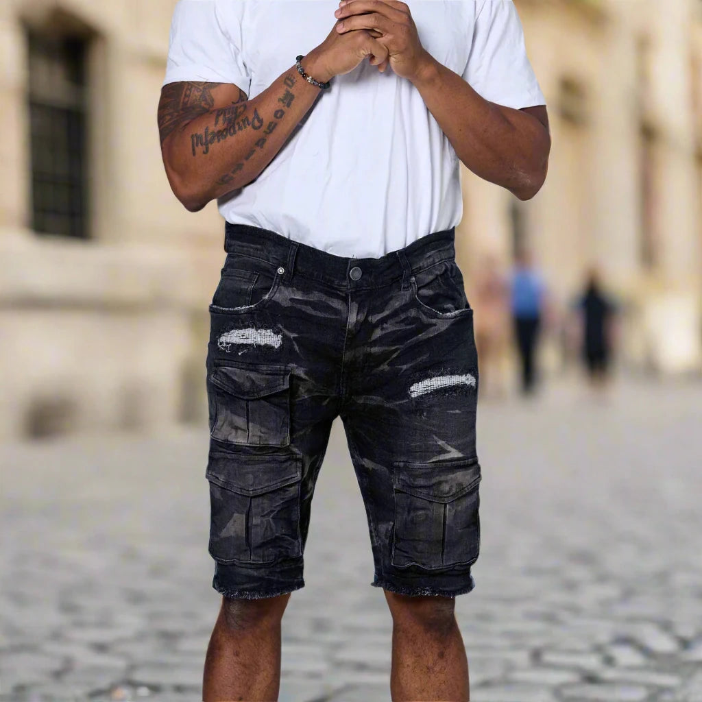 Person wearing black distressed cargo shorts and a white t-shirt on a blurred street background
