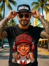 Man wearing a black t-shirt with 'Grooveman' design and a cap, standing outdoors with palm trees and buildings in the background.