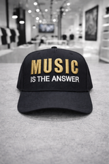 Black cap with 'Music is the Answer' text in a store setting