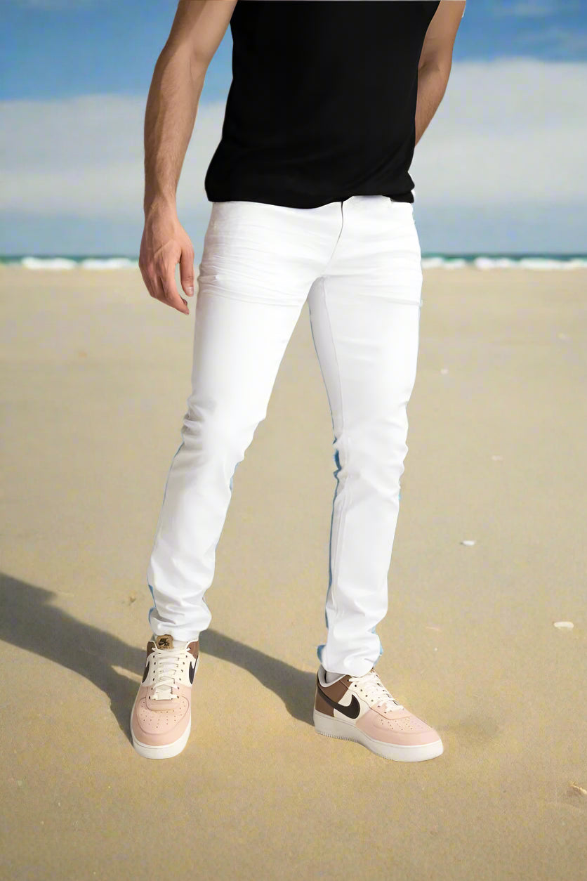 Person wearing white jeans and black shirt with beige sneakers on a neutral background