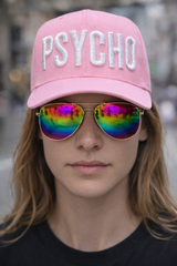 Person wearing a pink cap with 'PSYCHO' and colorful sunglasses.