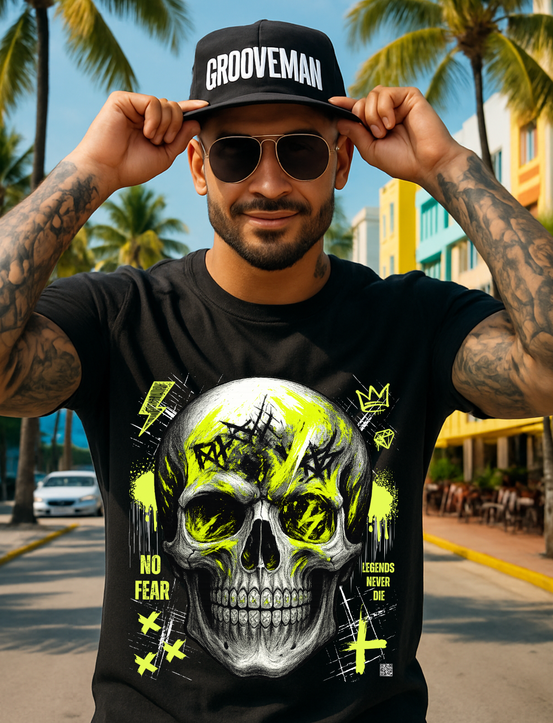 Man wearing a black t-shirt with a skull design and 'Grooveman' cap in a tropical setting.