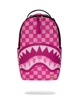 A pink and white patterned backpack with a shark mouth graphic on the front, featuring a top handle, black zippers, and a small gold brand plaque.