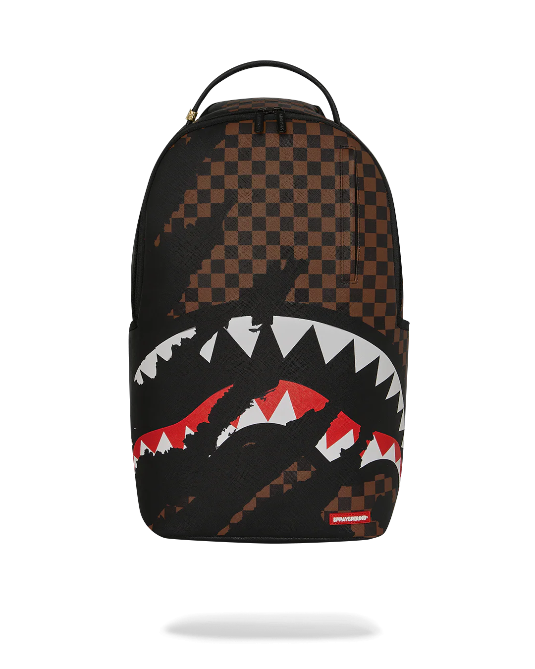 A Sprayground Shark backpack in black and brown checkerboard pattern, featuring a large shark mouth graphic with white and red details on the front pocket, shown against a plain white background.