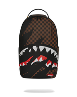 A Sprayground Shark backpack in black and brown checkerboard pattern, featuring a large shark mouth graphic with white and red details on the front pocket, shown against a plain white background.