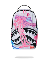 A Sprayground backpack featuring a pink cartoon character on a white background with graffiti-style graphics, including a shark mouth design.