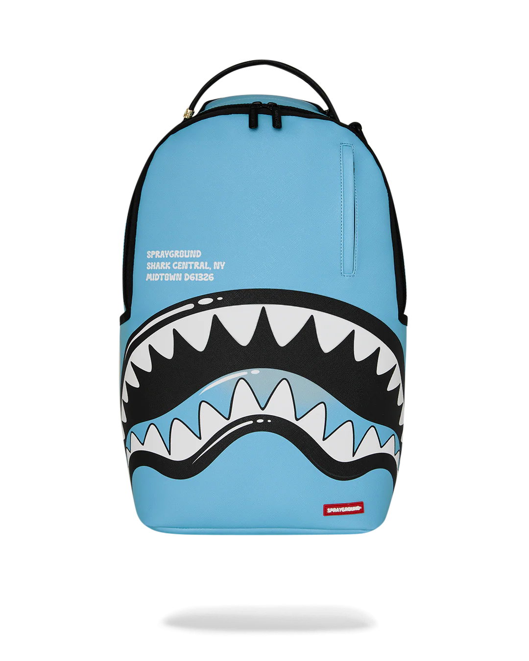 A light blue Sprayground Shark Central backpack featuring a large shark mouth graphic with white and black teeth across the lower front, plus a small red Sprayground logo patch near the bottom right.