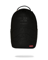 A black Sprayground Shark Central backpack with embossed shark mouth details and tonal black text on the front, shown against a plain white background with a soft shadow underneath.