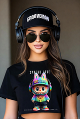 Woman wearing a black t-shirt with a colorful character and 'Spread Love Grooveman' text, paired with a black cap and headphones.
