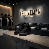 Black high-top sneakers on a stone surface with 'Grooveman' branding in the background.