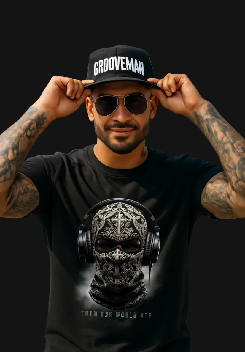 Man wearing a black t-shirt with a skull and headphones design, sunglasses, and a 'Grooveman' cap in a tropical setting.