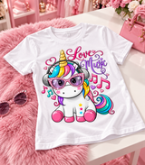 White Love Music unicorn T-shirt displayed on a white table with pink faux fur.